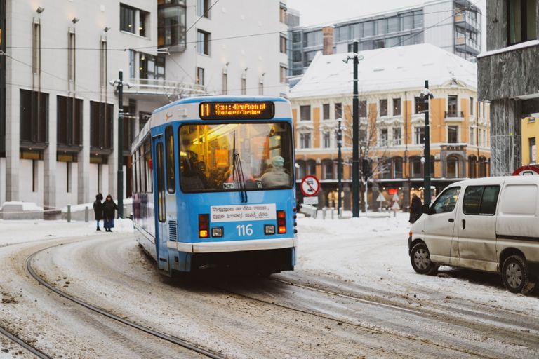 A blue tram moving along an Oslo street